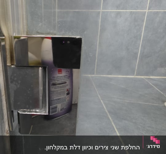 תקריב של ציר מתכת וגומי אוטם בדלת זכוכית של מקלחון